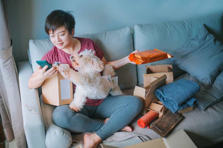 asian chinese mid adult woman happily unpacking opening all packages received all her parcel from online shopping with all her purchased delivered in living room sofa