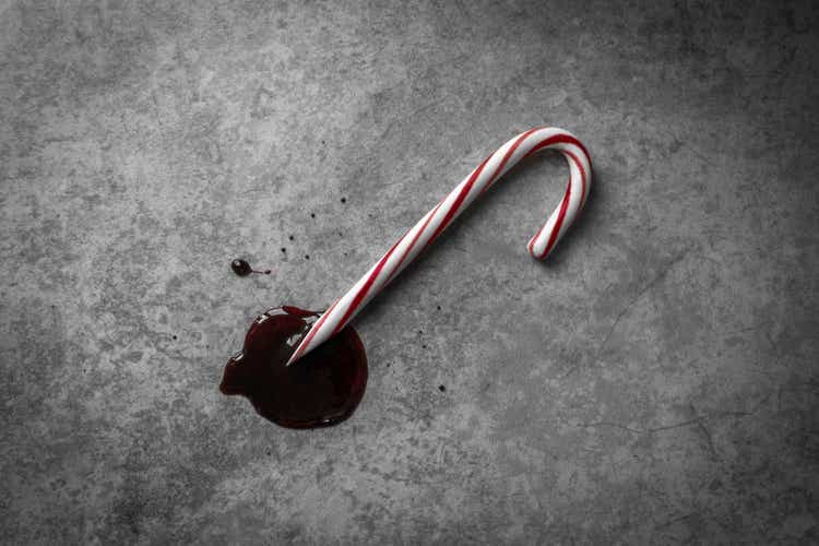 Moody Top-Down Shot of a Red and White Candy Cane, with a Sharpened Point lying in a Pool of Dark Red Blood-like Liquid