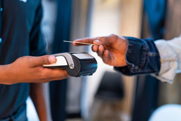 A store clerk extends his hand for the customer to pay by means of a dataphone when contacting his purchase