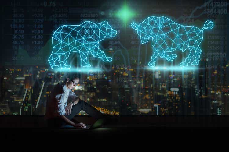 Asian businessman sitting and using the smart mobile phone showing Bull and Bear polygonal shape writing by lines and dots over Stock market exchange and Trading graph on the cityscape background