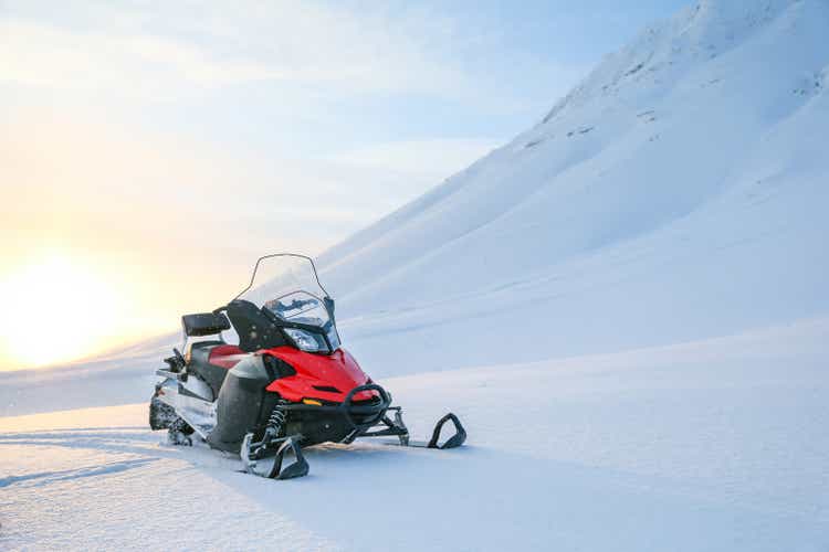 red snowmobile on a background of snowy mountains