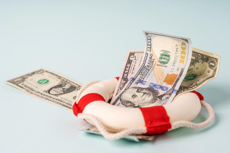 A lifebuoy with banknotes lie on a blue background, the concept of assistance and security in finance