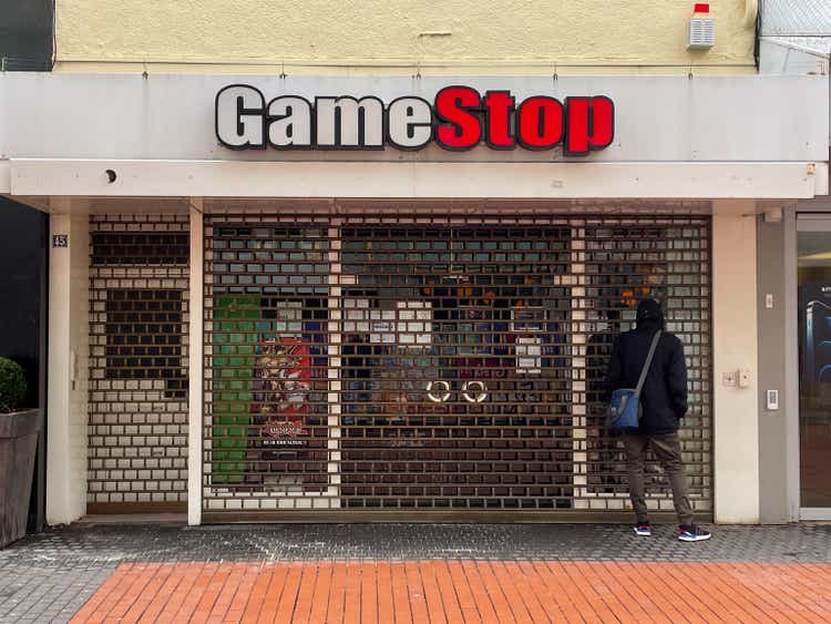 one person standing in front of closed gamestop store