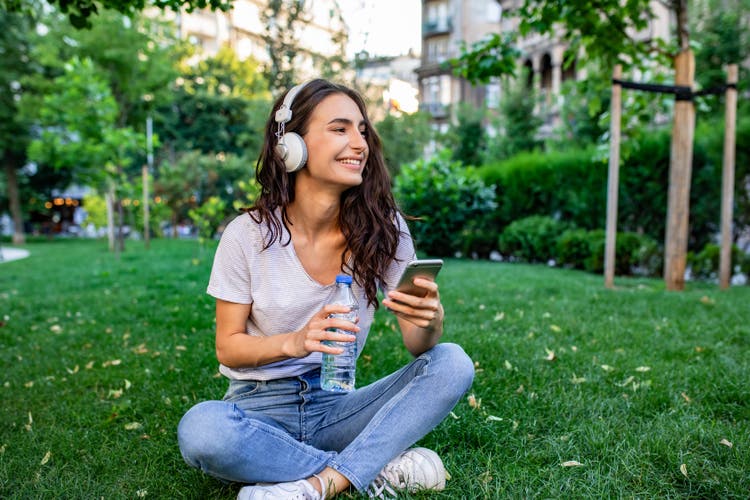Young woman sitting on the grass in park and relaxing