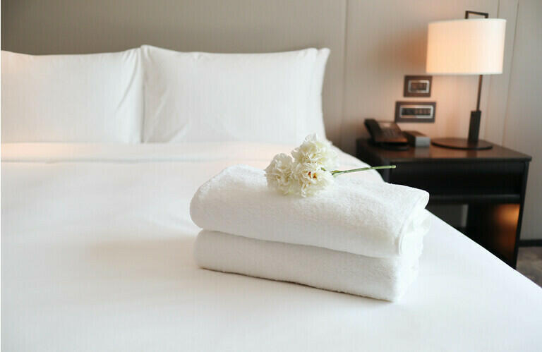 Schone witte badhanddoeken op de keurig schone slaapkamer - gezelligheid en schoon concept