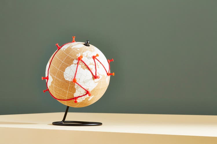A world globe with a journey marked in red string and pins