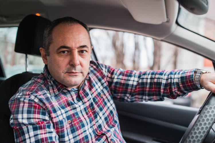 Mid aged man sitting comfortably in his car