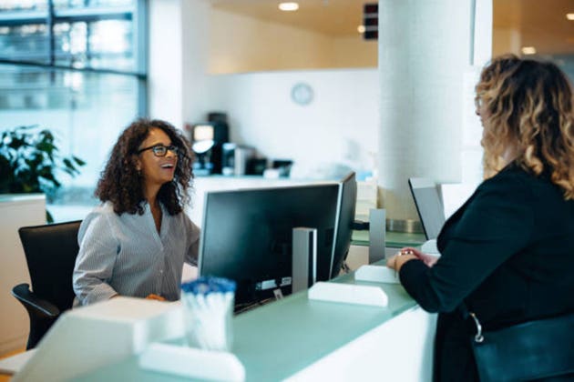 Friendly administrator assisting woman at reception desk