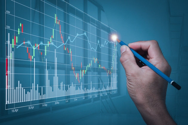 A man"s hand holding a pencil makes a gesture written on a stock chart that is making new highs. A blurry backdrop of the office"s large windows on high-rise buildings.