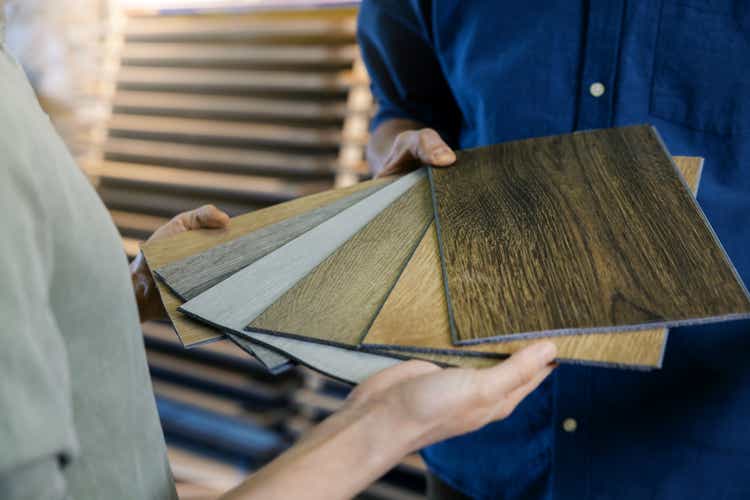 verkoper die houten materiaalsteekproeven van het textuurlaminaat aan klant toont