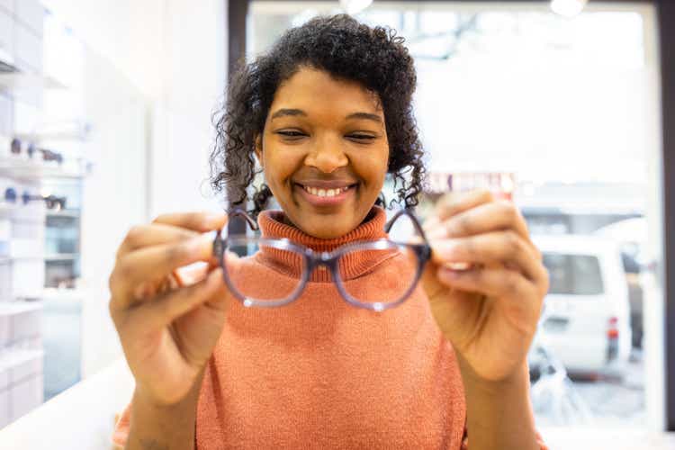 Female customer choosing new pair of glasses in optician shop