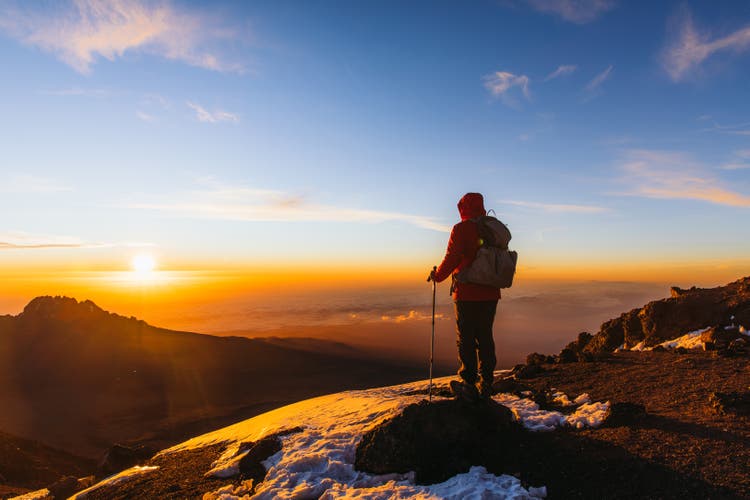 Man hiker achieved the dream enjoying the awe sunrise from the top of Kilimanjaro mountain