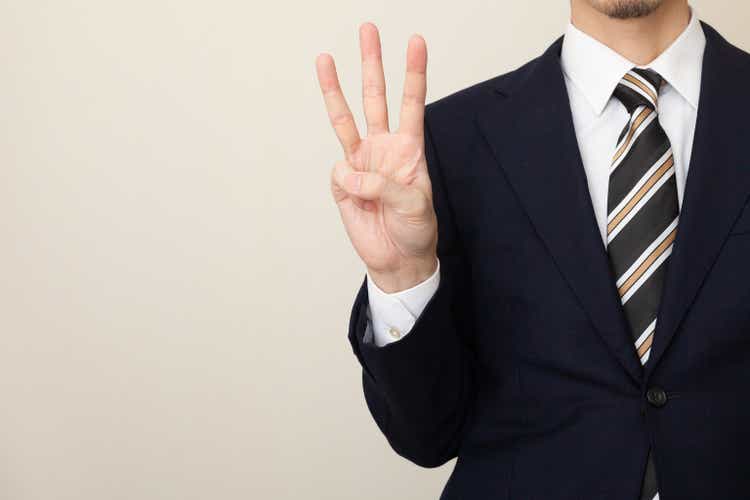 A man in a suit with three fingers
