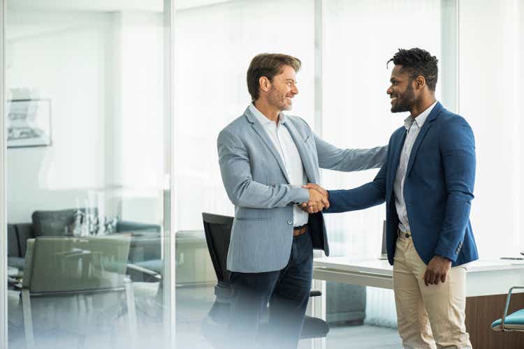 Smiling businessmen shaking hands in board room