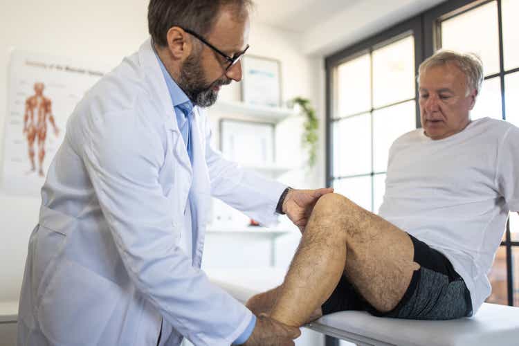 Doctor examining patient"s leg injury at doctor"s office