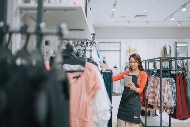 Asian chinese female boutique shop clothing store owner checking stock with digital tablet