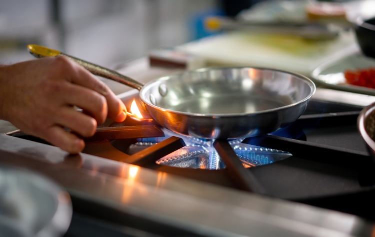 Chef-kok die een gasfornuisbrander met een gelijke aansteken