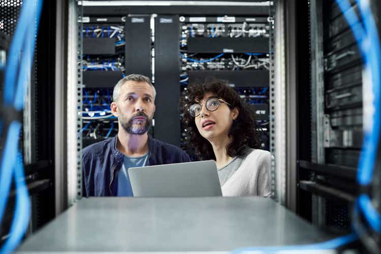 Female technician discussing with male coworker in server room