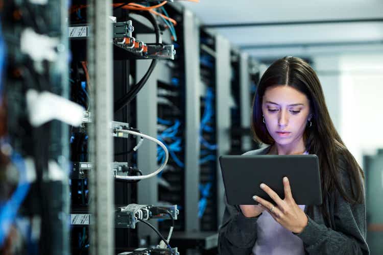 Female technician using digital tablet examining in server room