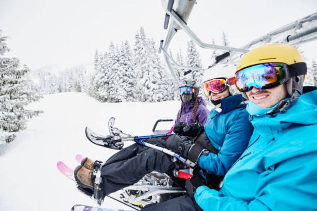 Portrait of smiling female adaptive athlete and friends riding chair lift at ski resort on winter morning