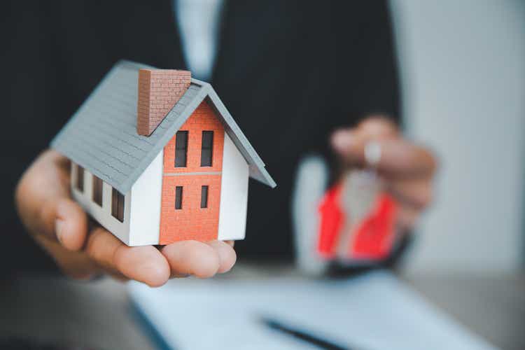 Брокеры по продаже домов предлагают продажу домов, модельный дом на стойке регистрации.  Недвижимость и жилые концепции, торговля домами