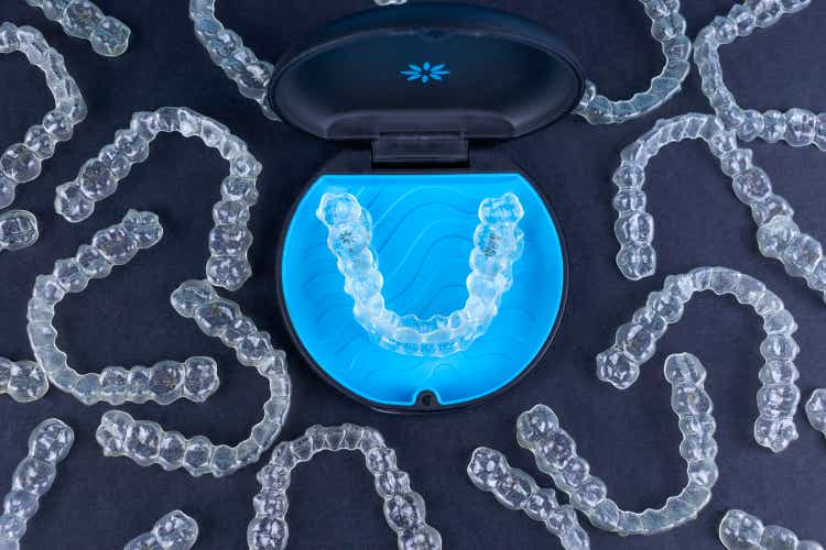 Plastic case with invisible transparent orthodontic retainers invisalign on black background. Aligner brackets or braces dental container