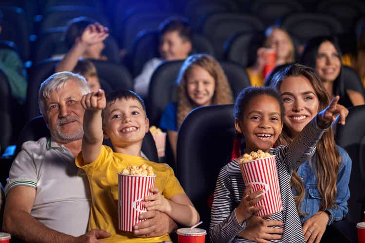 Parents with kids on knees in cinema.