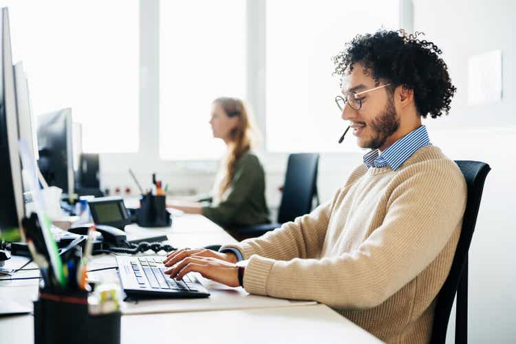 Man Working At Computer And Talking To Clients On Phone