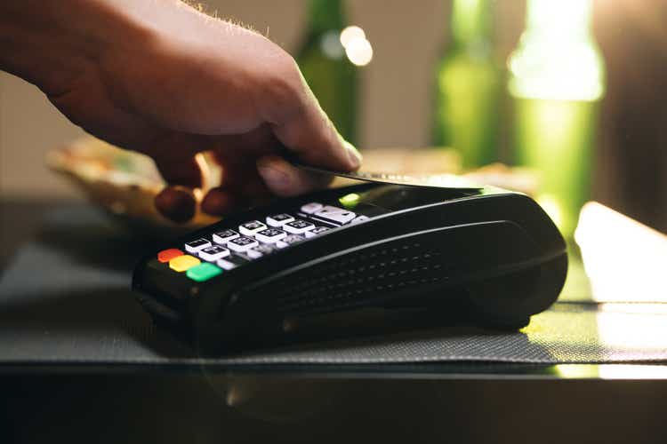Credit card machine for money transaction. Close up of male hold in hand wireless modern bank payment terminal to process acquire credit card payments black card. Credit card through pos terminal