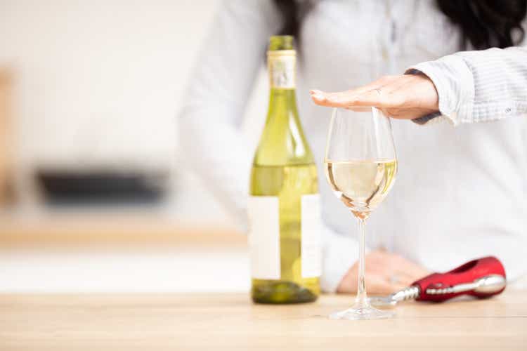 Woman holding hand above the glass of white wine to express she had enough.