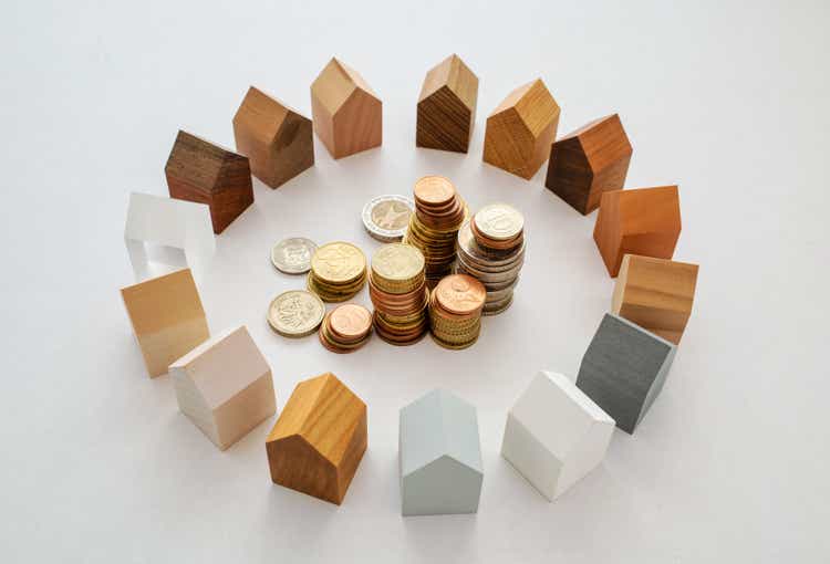 Coins and a circle of wooden models of houses
