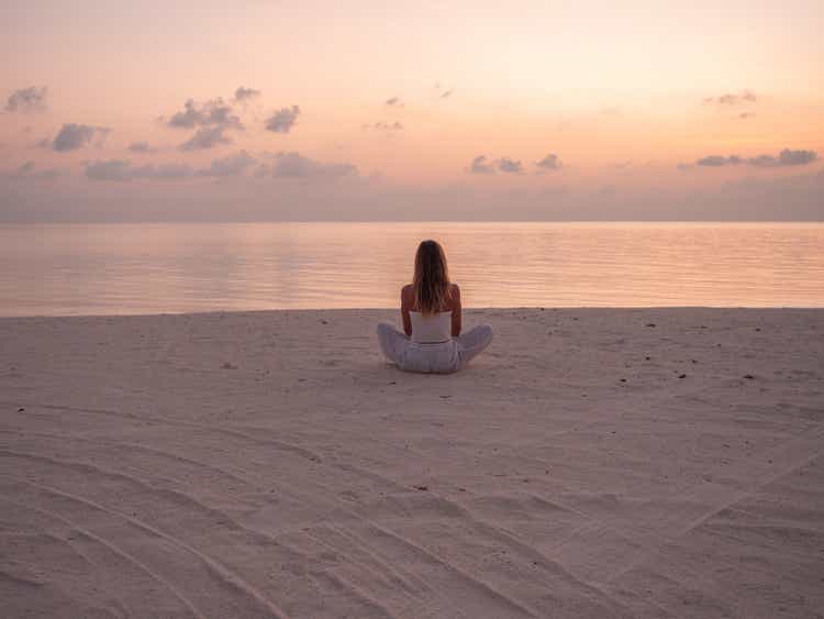 Woman exercising yoga at sunrise on the beach