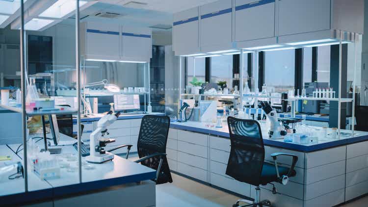 Empty modern biological science laboratory with technical microscope, glass test tubes, micropipettes and desktop computer with display.