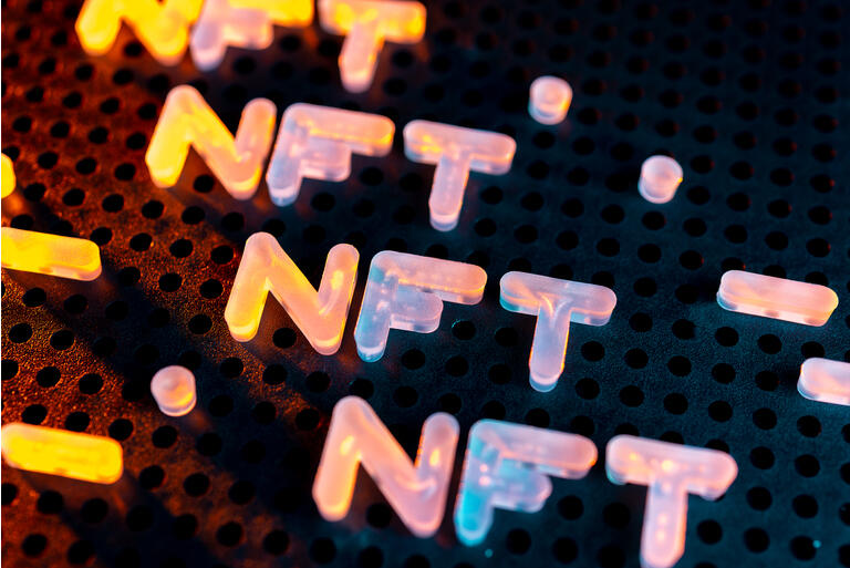 NFT nonfungible tokens text from letters glowing with neon light on a dark background