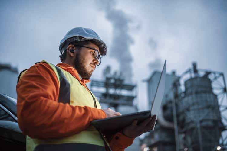 Serious handsome engineer using a laptop while working in the oil and gas industry.