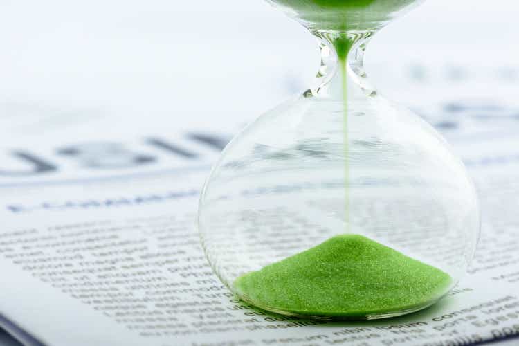 Green sand clock / hourglass timer on business report or daily report