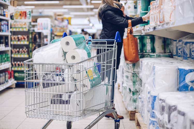Woman shopping at supermarket choosing toilet paper.