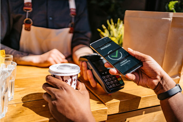Woman paying via contactless channel by mobile banking application