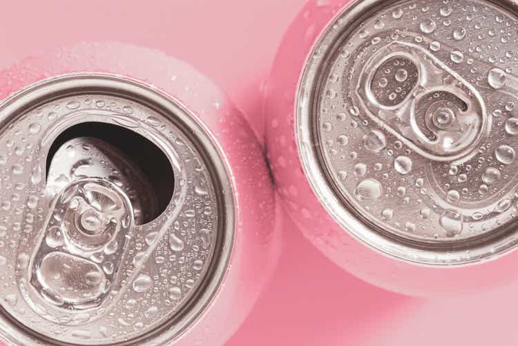Pink soda cans in water drops, top view