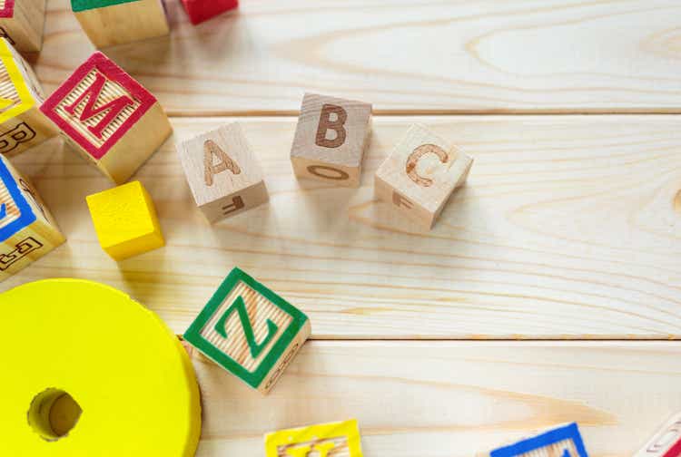 Wooden kids cubes ABC on wooden table. Educational toys blocks, pyramid, pencils, numbers. Toys for kindergarten, preschool or daycare. Copy space for text. Top view