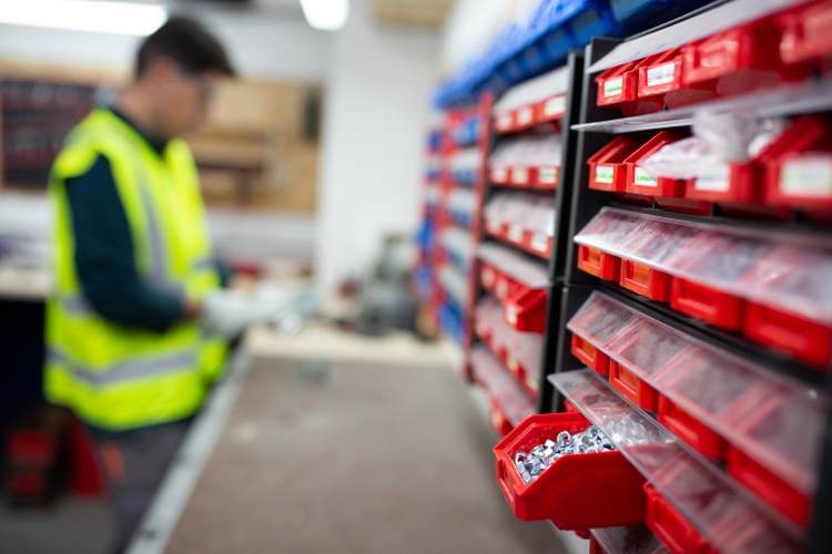 Engineer with protecive gloves taking material from the warehouse.