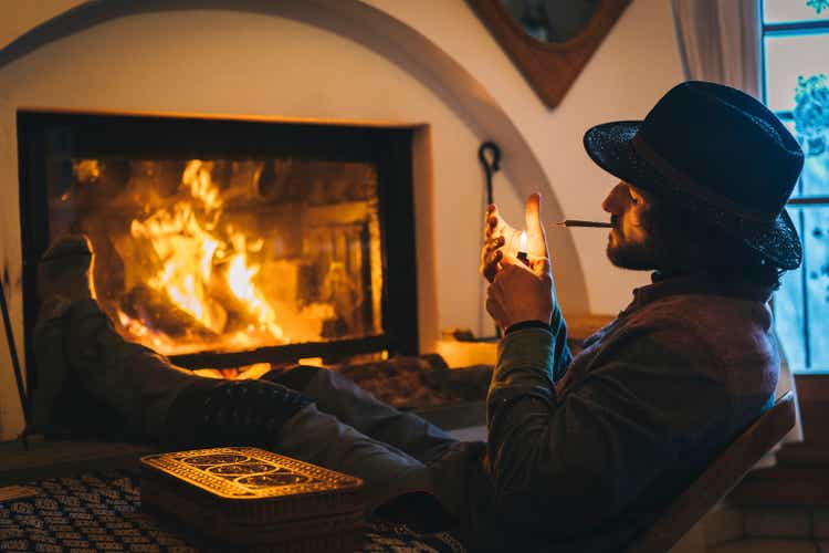 Young man relaxes by fire and smokes cbd joint