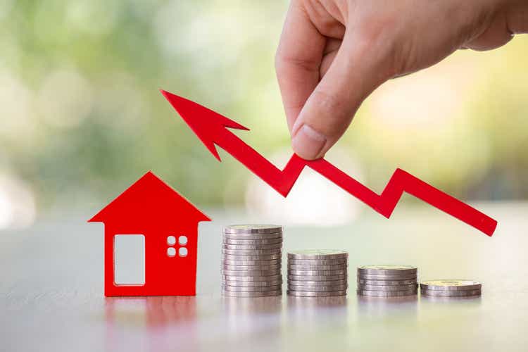 Hand holding graph over the Increasing house miniature. Property investment and house mortgage financial concept, Investment property, Real estate, Saving money.