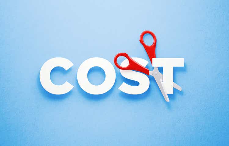 Cutting Costs Concept - Scissors Cutting The Word Cost Over Blue Background