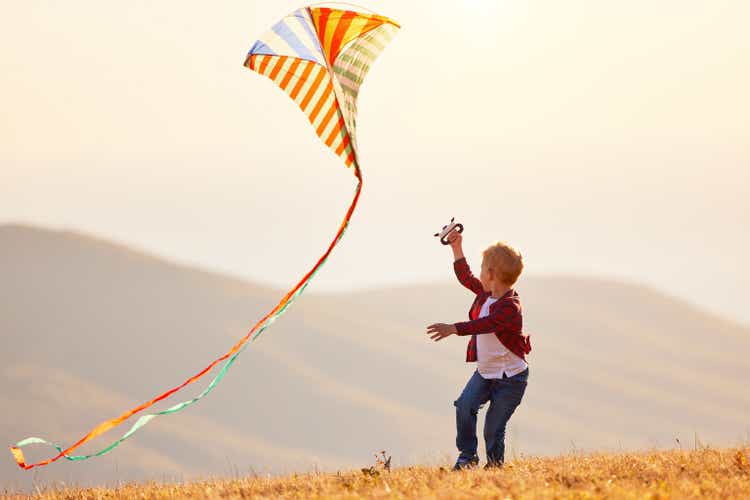 happy child boy running with kite at sunset outdoors