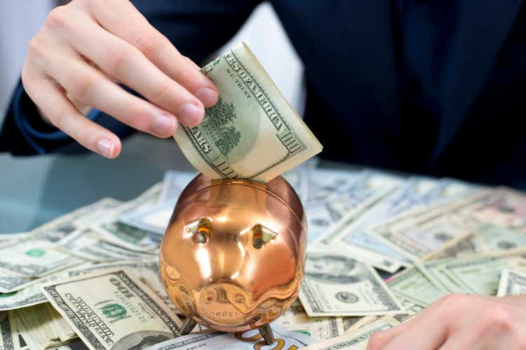 Business Man putting money in copper piggy bank