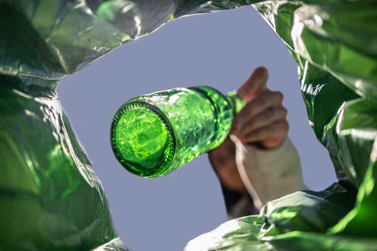 Unrecognisable woman recycles a green beer bottle