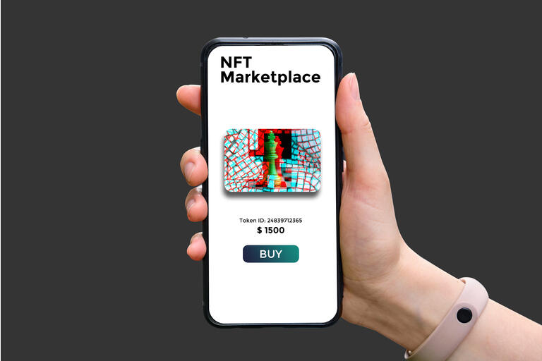 Hand holds smartphone with type of cryptographic NFT marketplace with art sale.