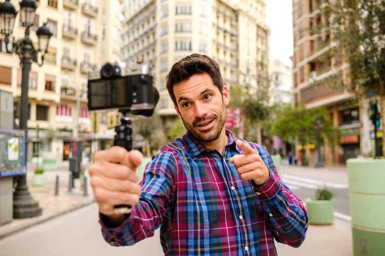 Young Latino adult man records a video with a camera in a city