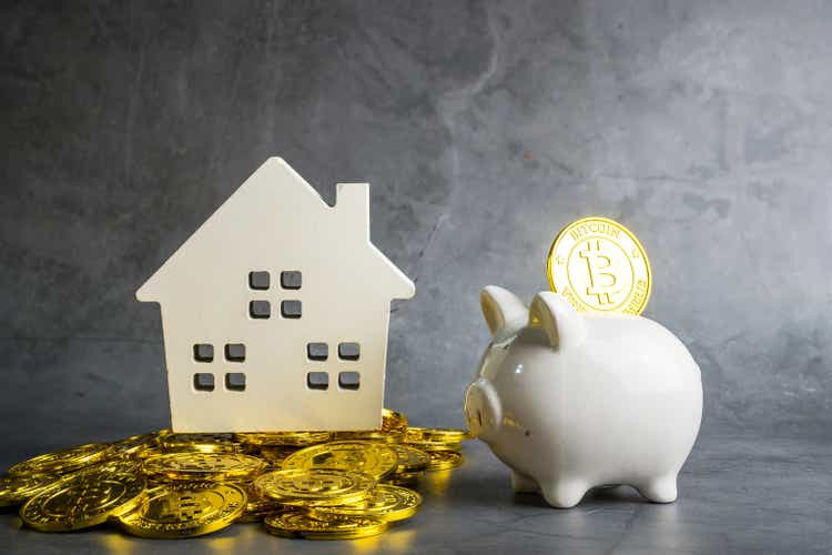 Bitcoin money with piggy bank and wooden home model on the table , business and finance concept. save money concept.Bitcoin finance in the digital age
